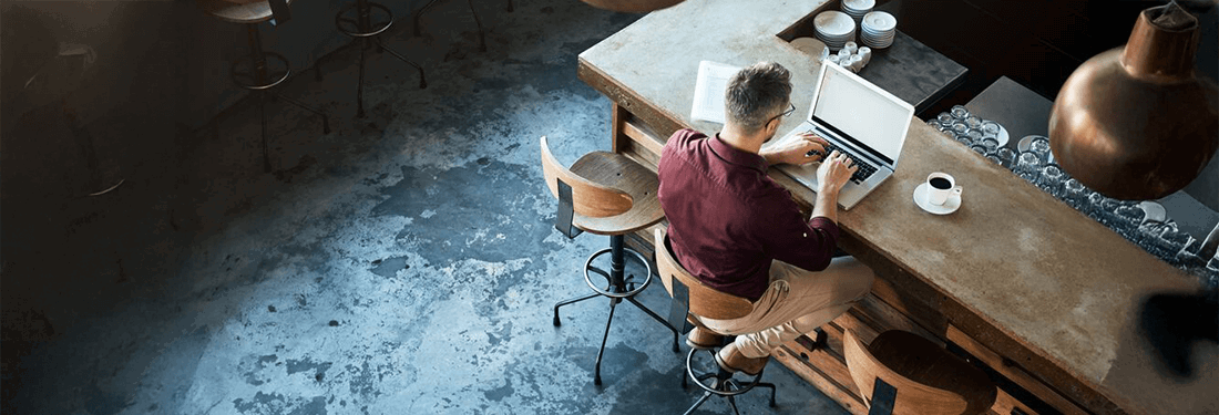 high angle shot of a businessman working on his laltop at the bar in a cafe