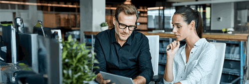 Two colleagues talking and looking at a device