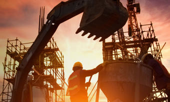 Silhouetted construction workers collaborating at sunset