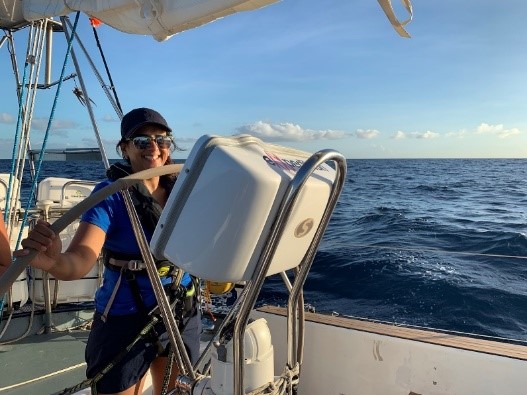 Pindy smiling and standing at the helm, with the wheel in her hands